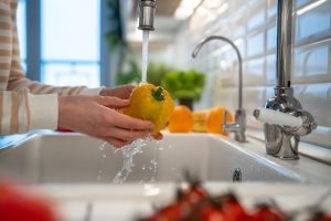 A water filtration system from H2O Concepts can help solve Yuma Hard Water issues image shows vegetable being washed with kitchen sink water