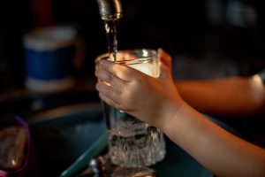 Start getting rid of Maricopa Hard Water problems by working with H2O Concepts image shows hands holding glass under sink faucet