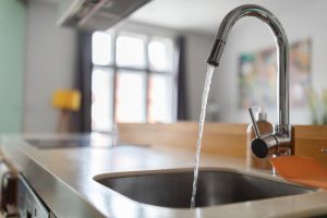 Tackle Queen Creek Hard Water problems in your home with H2O Concepts solutions image shows water running from kitchen faucet